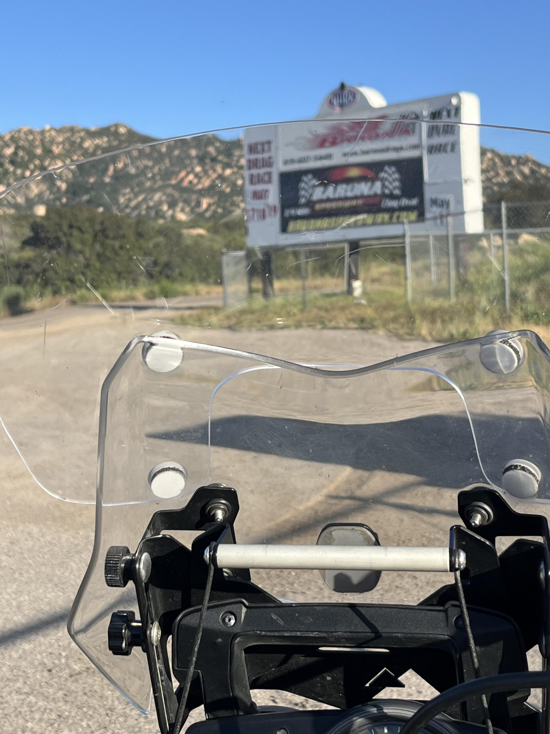 A motocross raceway sign seen through the windshield of a motorcycle in the San Diego mountains