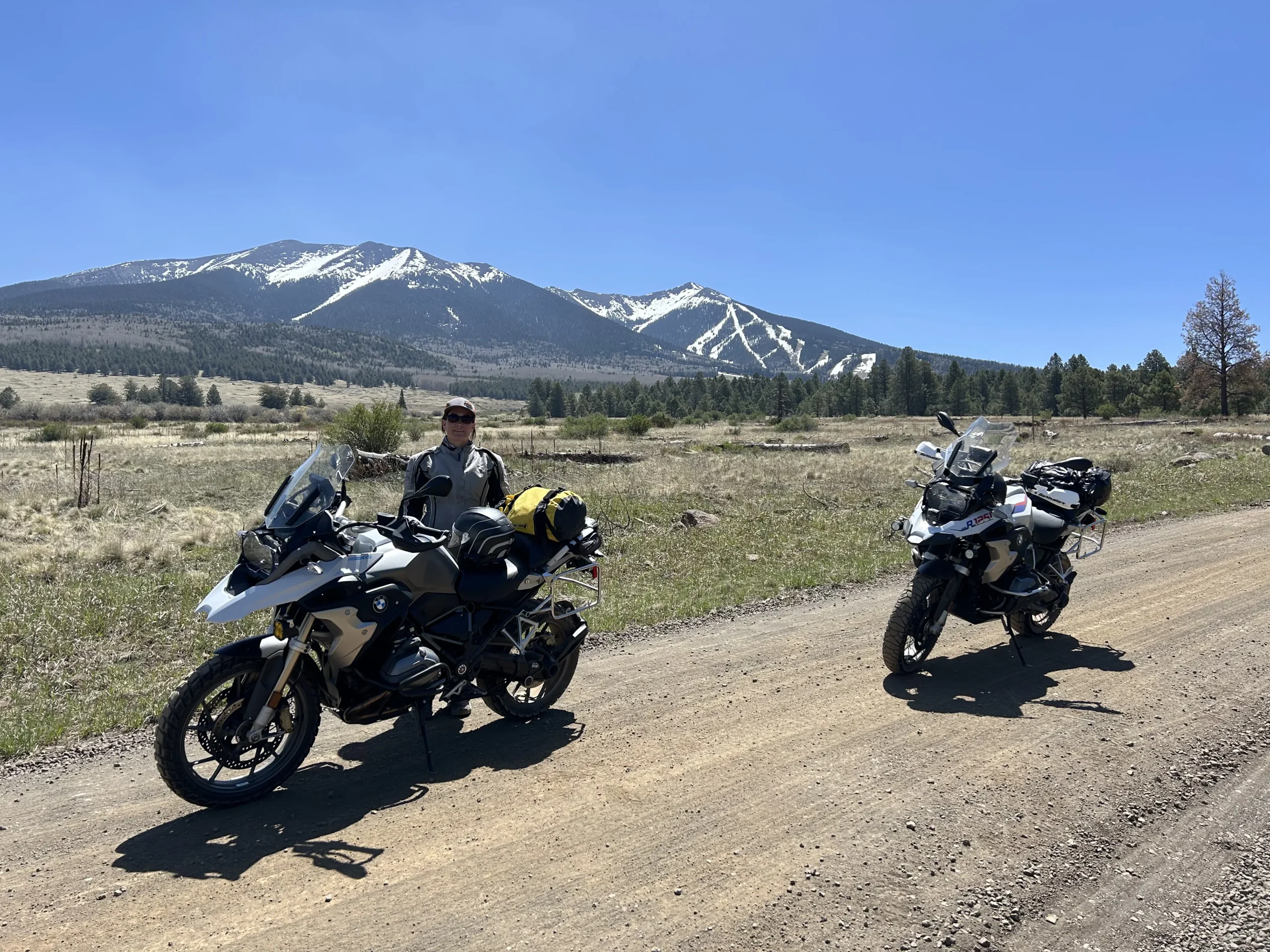 Two BMW adventure motorcycles in front of the snowcapped Mt. Humphreys, Arizona's tallest point