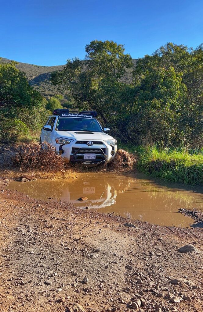 A Toyota 4runner charges through a puddle of muddy water in the Otay Mountain Wilderness Area